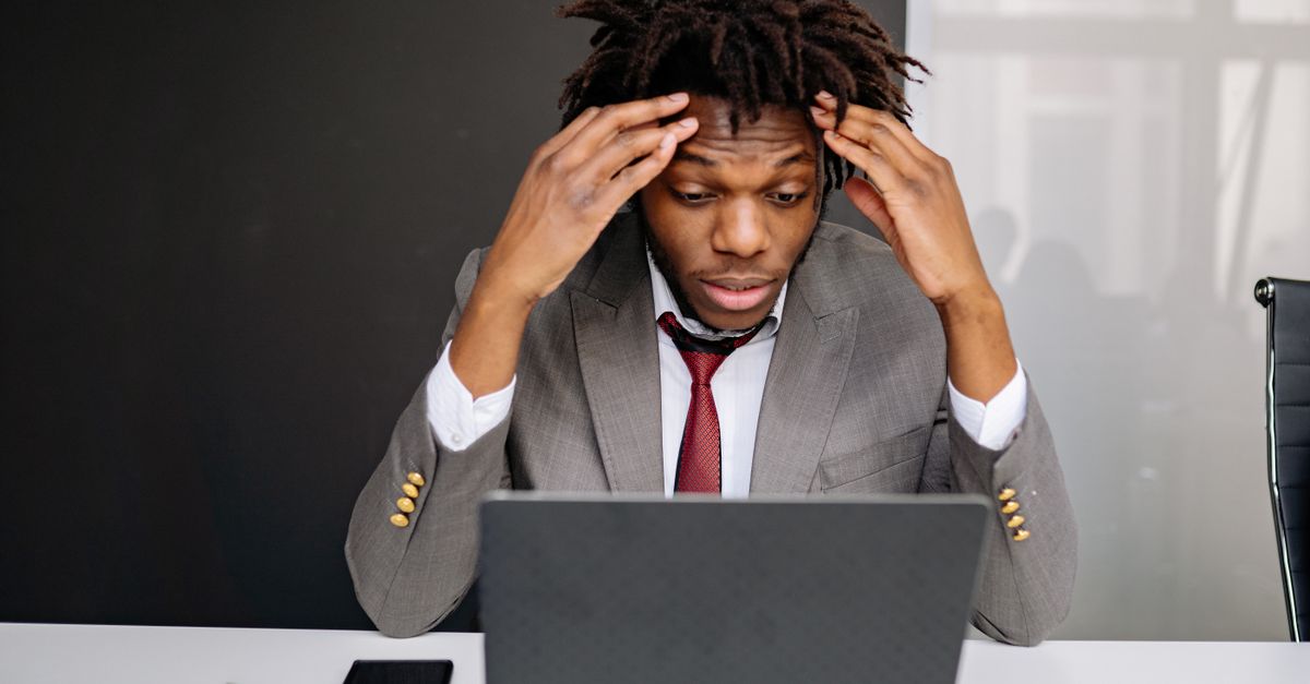 African American businessman experiencing stress while working on a laptop indoors.