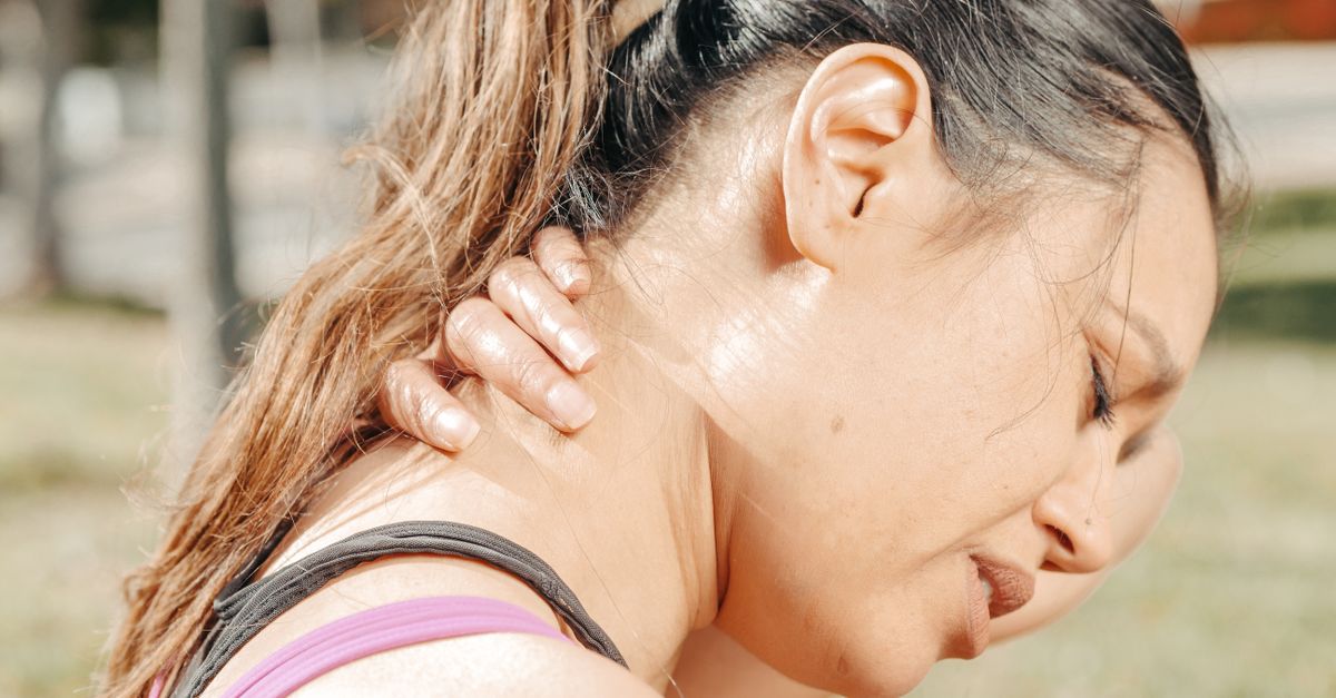 Woman holding her neck showing tech neck discomfort and strain from looking down at a screen.