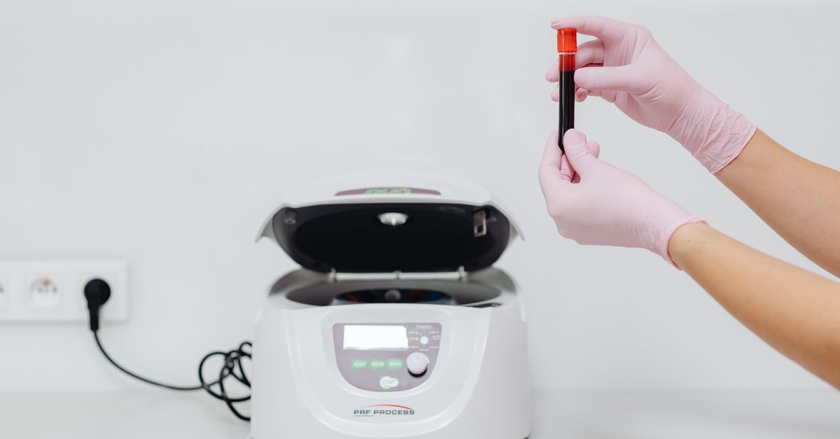 Medical professional handling blood sample in a centrifuge for laboratory testing.